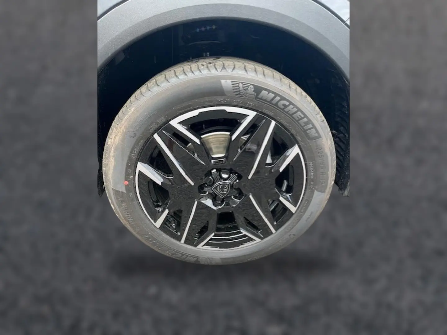 Gros plan sur la roue avant droite du Peugeot 3008 gris titane avec jante alu noire et détails argentés.