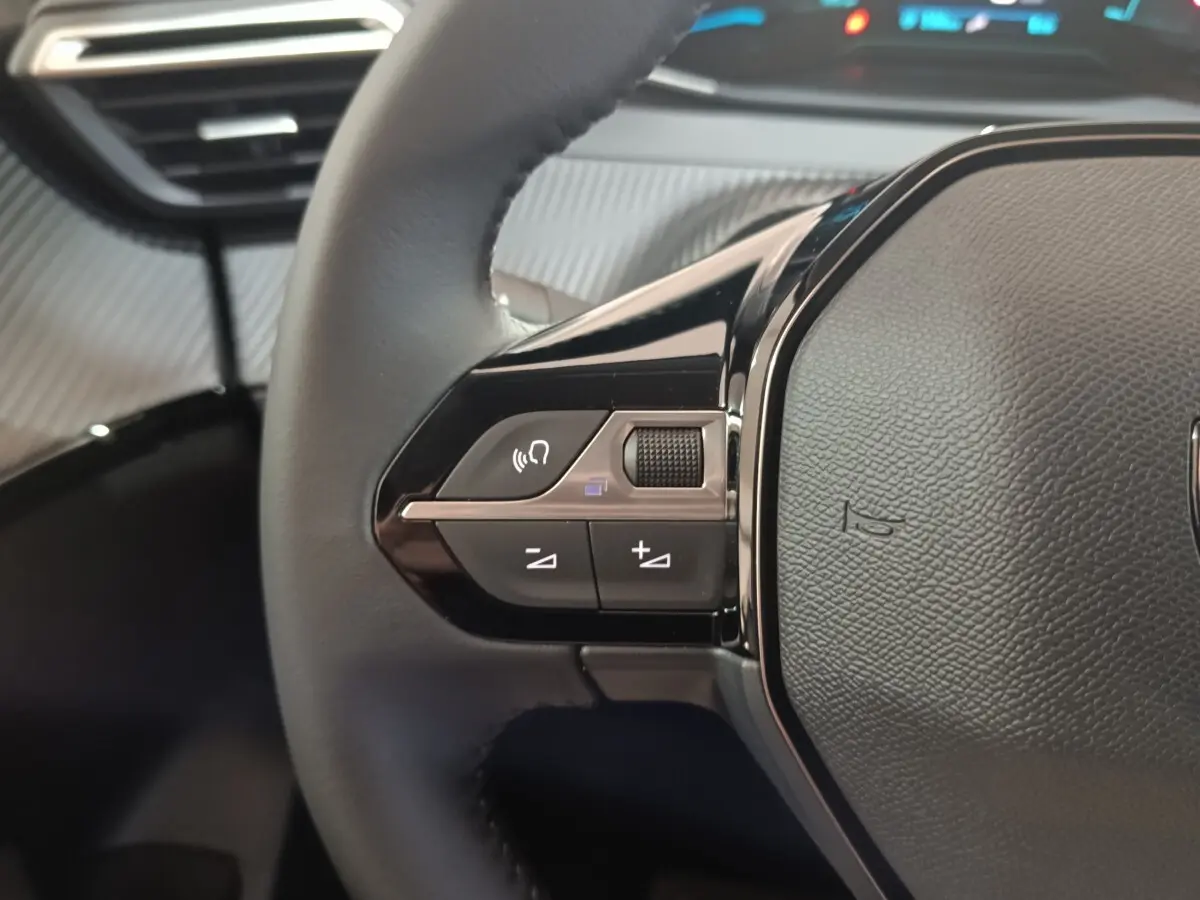 Gros plan sur le côté gauche du volant cuir multifonctions du Peugeot 208 électrique gris clair 2024.