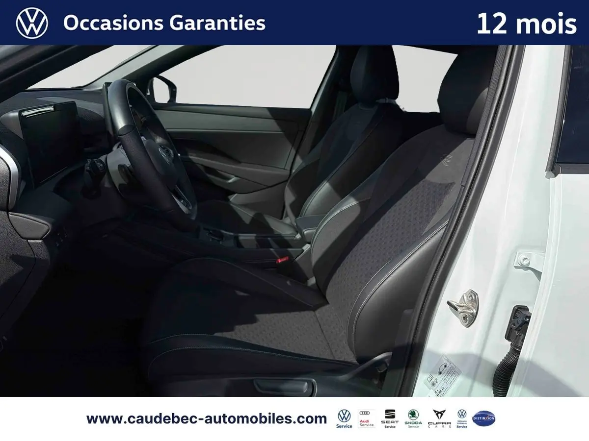Vue intérieure côté conducteur du Volkswagen T-Roc blanc 2025, montrant les sièges sport et le volant multifonction cuir.