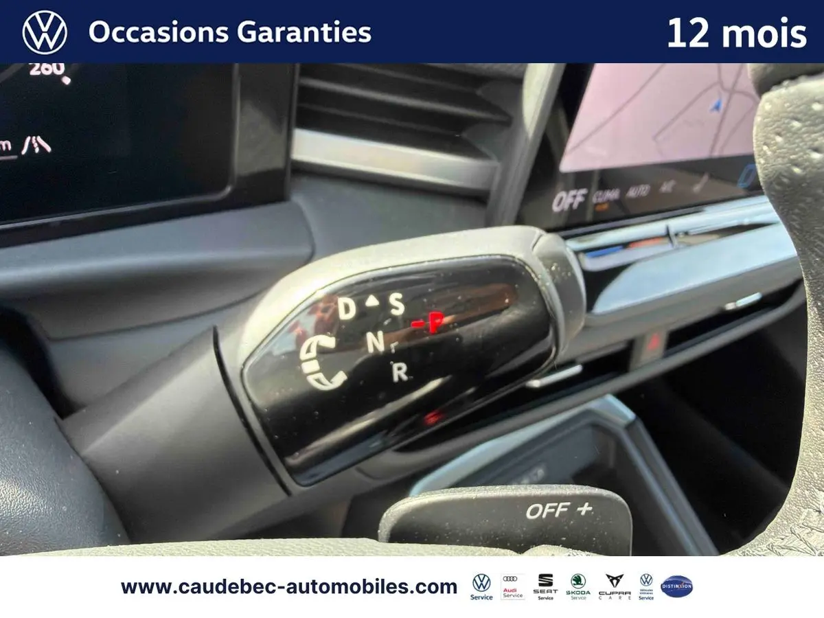 Gros plan sur le levier de vitesses DSG7 noir brillant du Volkswagen T-Roc blanc, avec tableau de bord en arrière-plan.