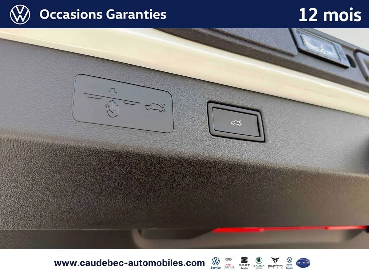 Gros plan sur le bouton d'ouverture électrique du hayon du Volkswagen T-Roc blanc, intérieur du coffre visible.