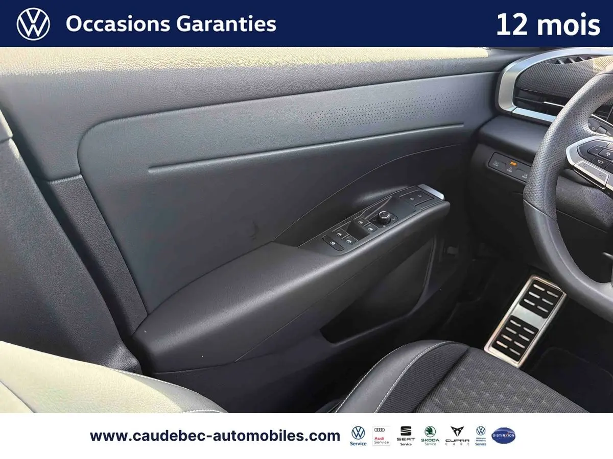 Vue intérieure côté conducteur du Volkswagen T-Roc blanc, mettant en valeur la porte avec commandes électriques et volant multifonction.