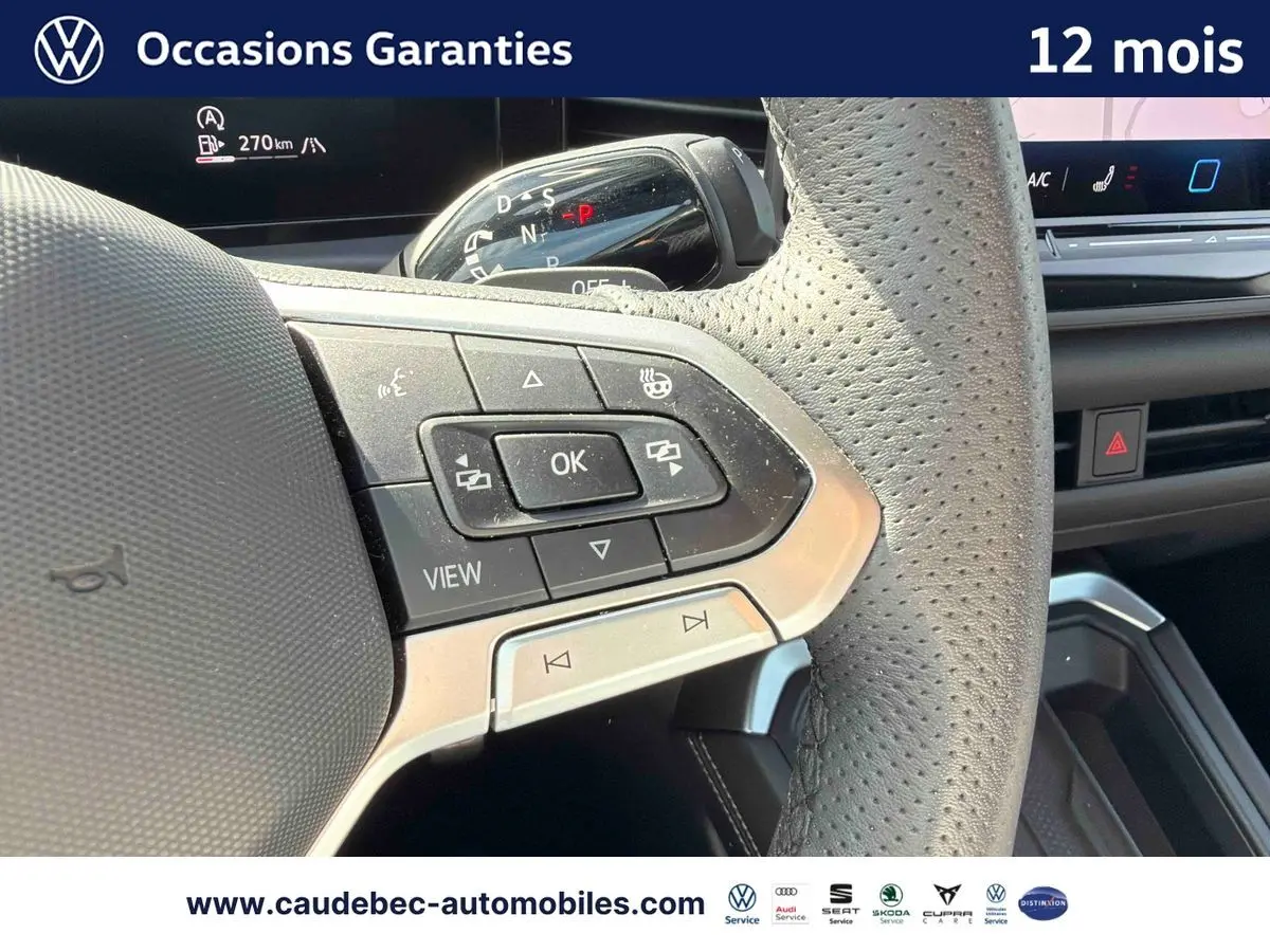 Gros plan sur le volant cuir perforé du Volkswagen T-Roc 2025 avec commandes multifonctions et palettes au volant.