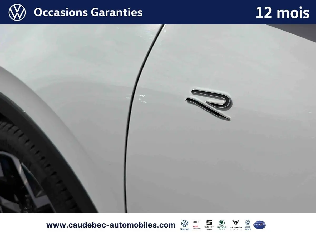 Détail du logo "R" sur la porte côté gauche d'un Volkswagen T-Roc blanc, jante noire visible en arrière-plan.