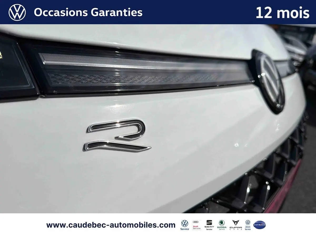 Gros plan sur la calandre avant blanche du Volkswagen T-Roc avec logo VW et badge R lumineux.