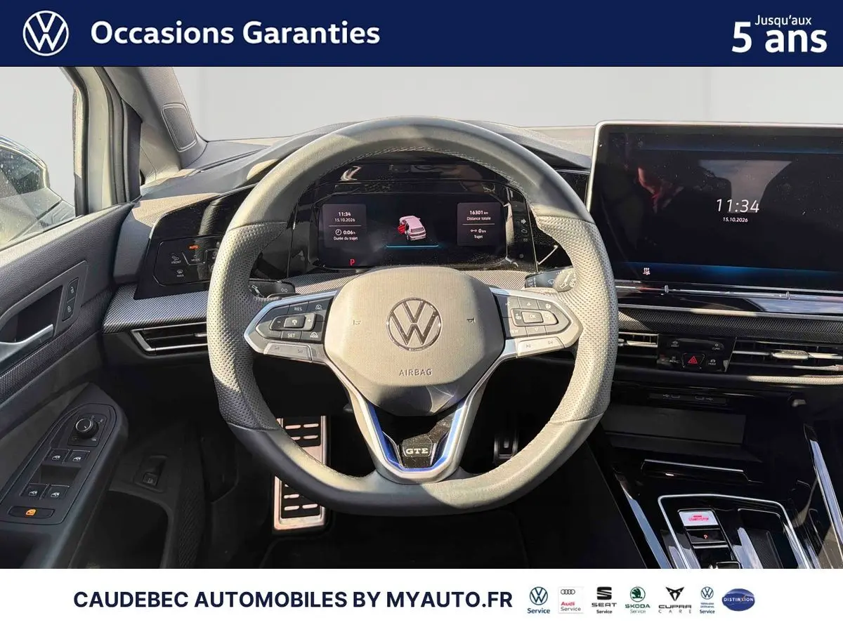 Vue intérieure centrée sur le volant sport multifonction GTE et le tableau de bord digital de la Volkswagen Golf 1.5 eHybrid blanche.