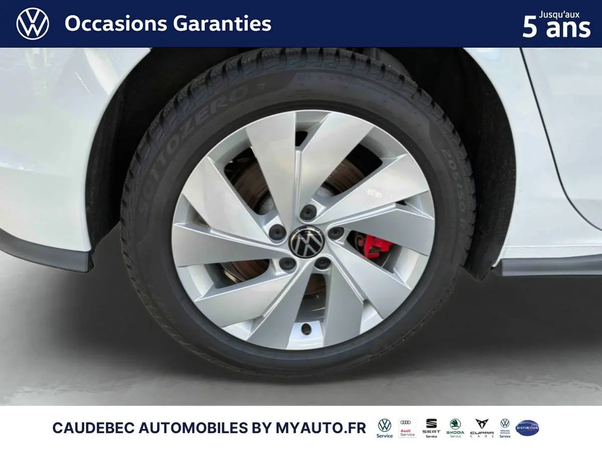 Gros plan sur la roue avant droite d'une Volkswagen Golf 1.5 eHybrid blanche avec jante alliage 17'' et étrier de frein rouge.