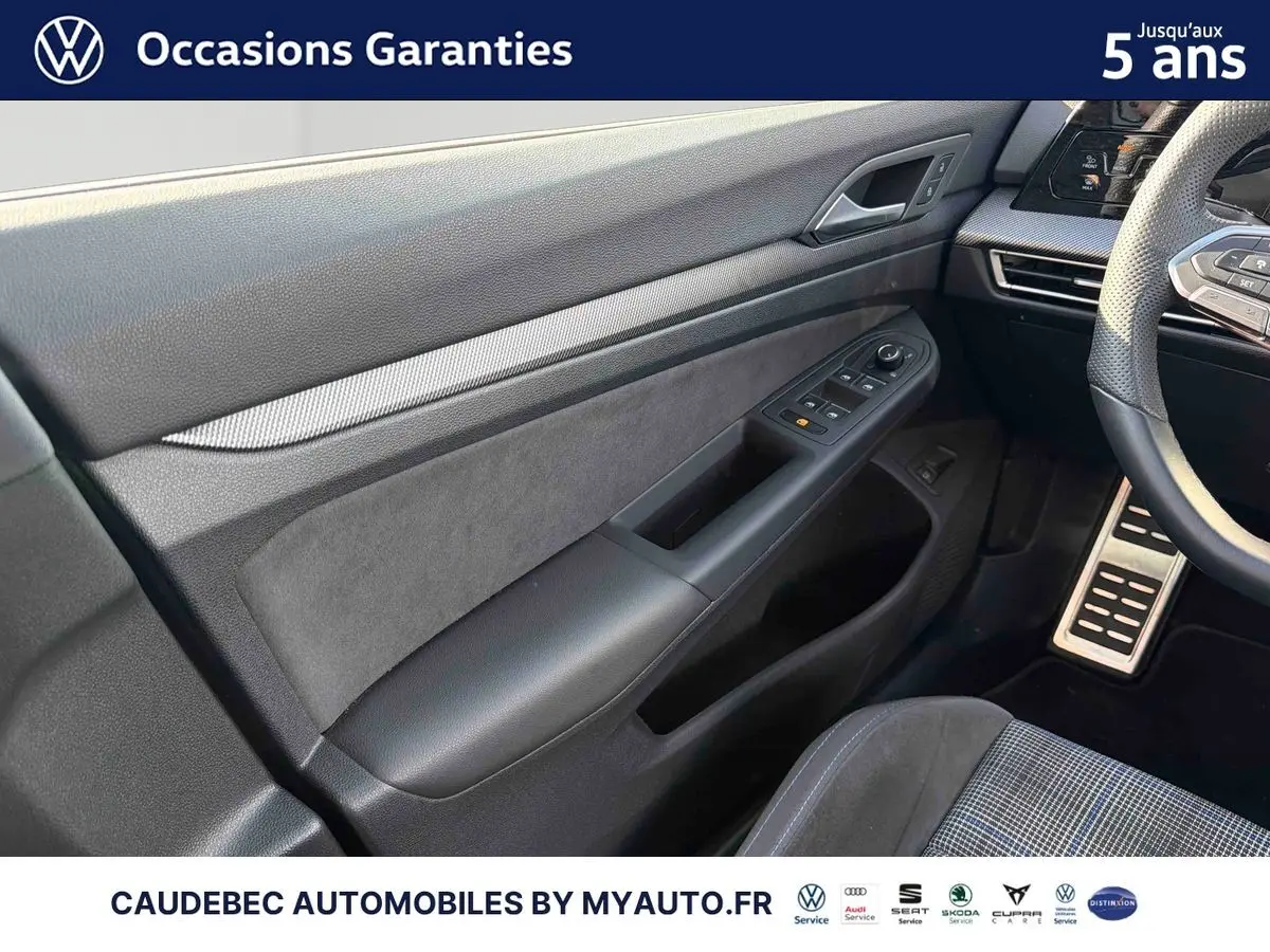 Vue intérieure côté conducteur de la porte et partie du tableau de bord d'une Volkswagen Golf 1.5 eHybrid blanche.