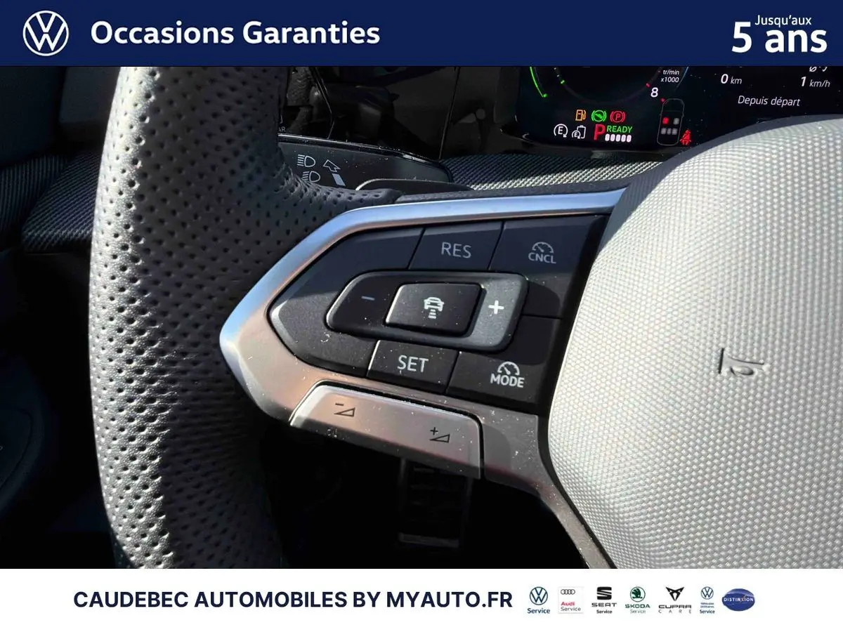 Gros plan sur le volant perforé gris clair de la Volkswagen Golf 1.5 eHybrid 2026 avec commandes intégrées.
