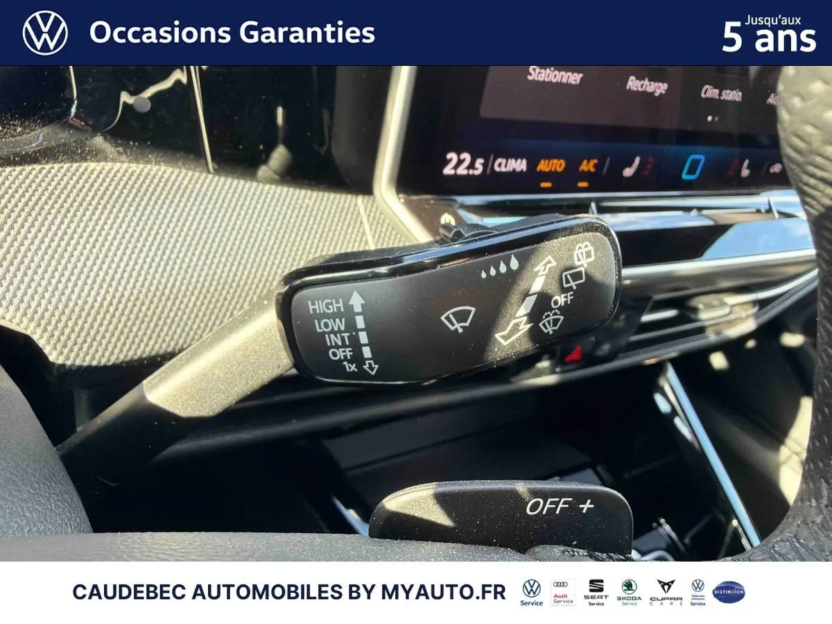Gros plan sur la commande d’essuie-glace à gauche du volant dans l’habitacle lumineux d’une Volkswagen Golf blanche.