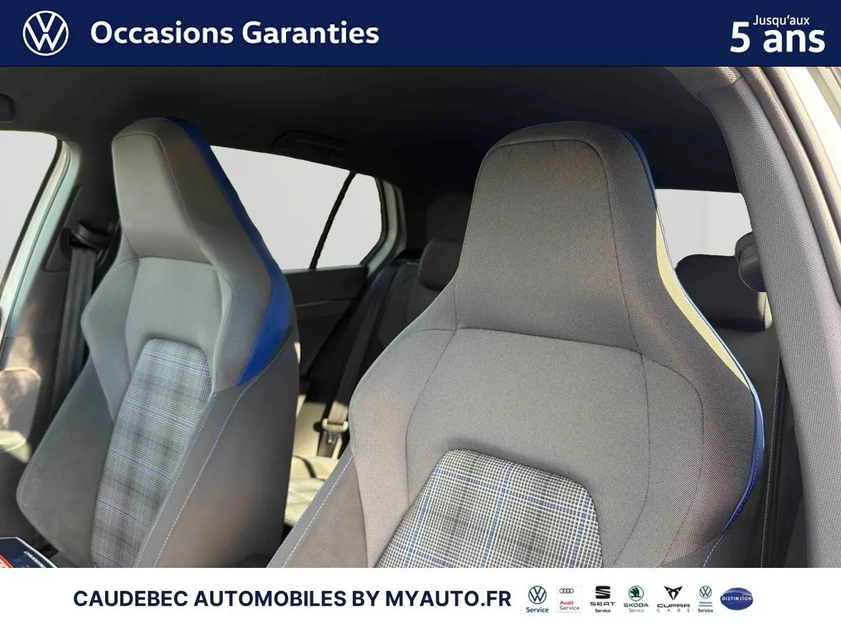 Gros plan sur les sièges avant sport gris avec surpiqûres bleues et tissu à carreaux de la Volkswagen Golf 1.5 eHybrid blanche.