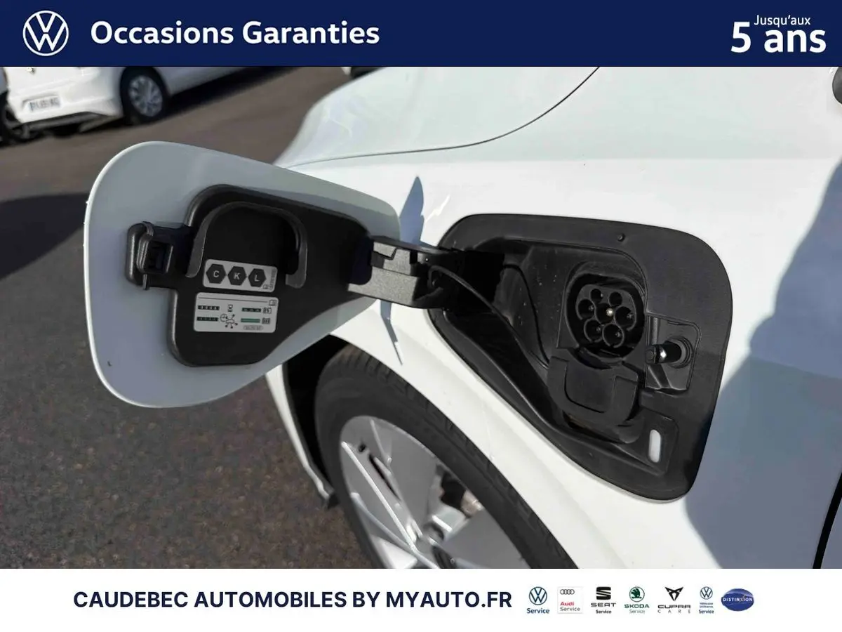 Vue rapprochée de la trappe de recharge ouverte côté gauche d’une Volkswagen Golf 1.5 eHybrid blanche, avec prise électrique visible.