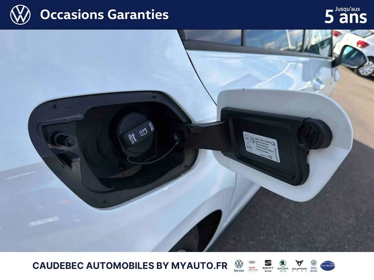 Vue rapprochée de la trappe à carburant ouverte côté gauche d'une Volkswagen Golf 1.5 eHybrid blanche, montrant le bouchon.