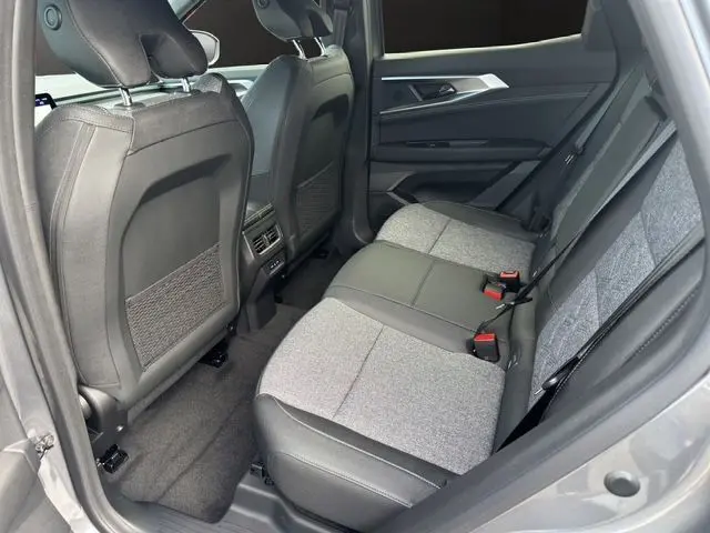 Vue intérieure arrière droite du Renault Austral PH2 Techno hybride 2025, sièges bi-matière gris et noir avec ceintures rouges.