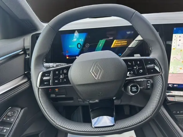 Volant multifonction noir avec logo Renault au centre, tableau de bord numérique et écran tactile du Renault Austral PH2 hybride 2025.