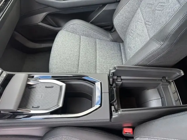Vue intérieure rapprochée du coffre central ouvert et siège avant gris clair du Renault Austral PH2 Techno hybride 2025.