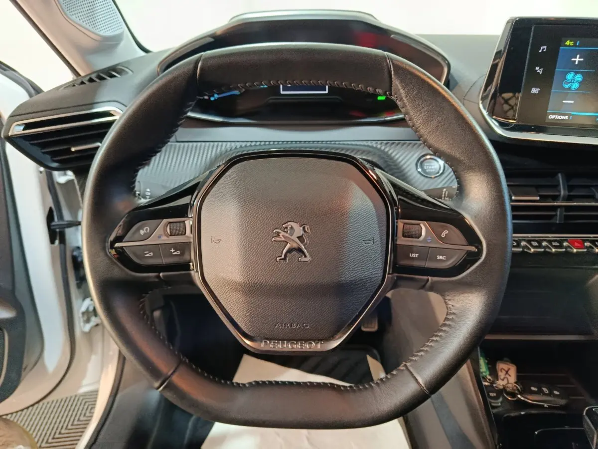 Vue rapprochée du volant cuir multifonctions noir du Peugeot 208 électrique Active Business 2020 avec tableau de bord numérique.