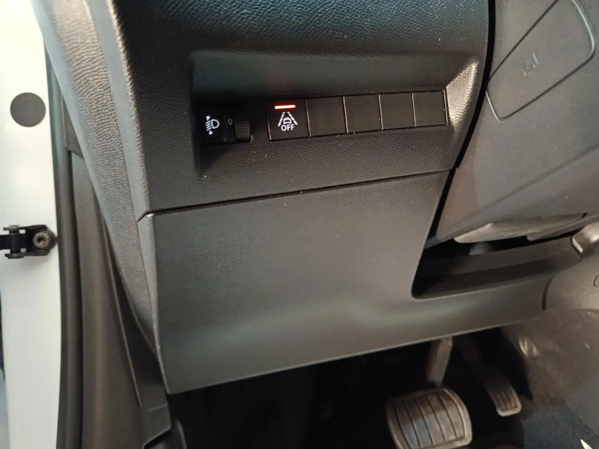 Vue rapprochée côté gauche du tableau de bord noir avec commandes d'assistance et pédales du Peugeot 208 blanc électrique.