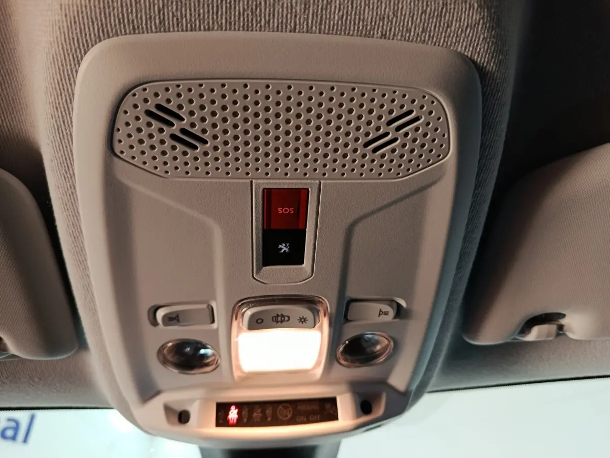 Vue en contre-plongée du plafonnier intérieur gris clair du Peugeot 208 Electrique Active Business avec bouton SOS rouge allumé.