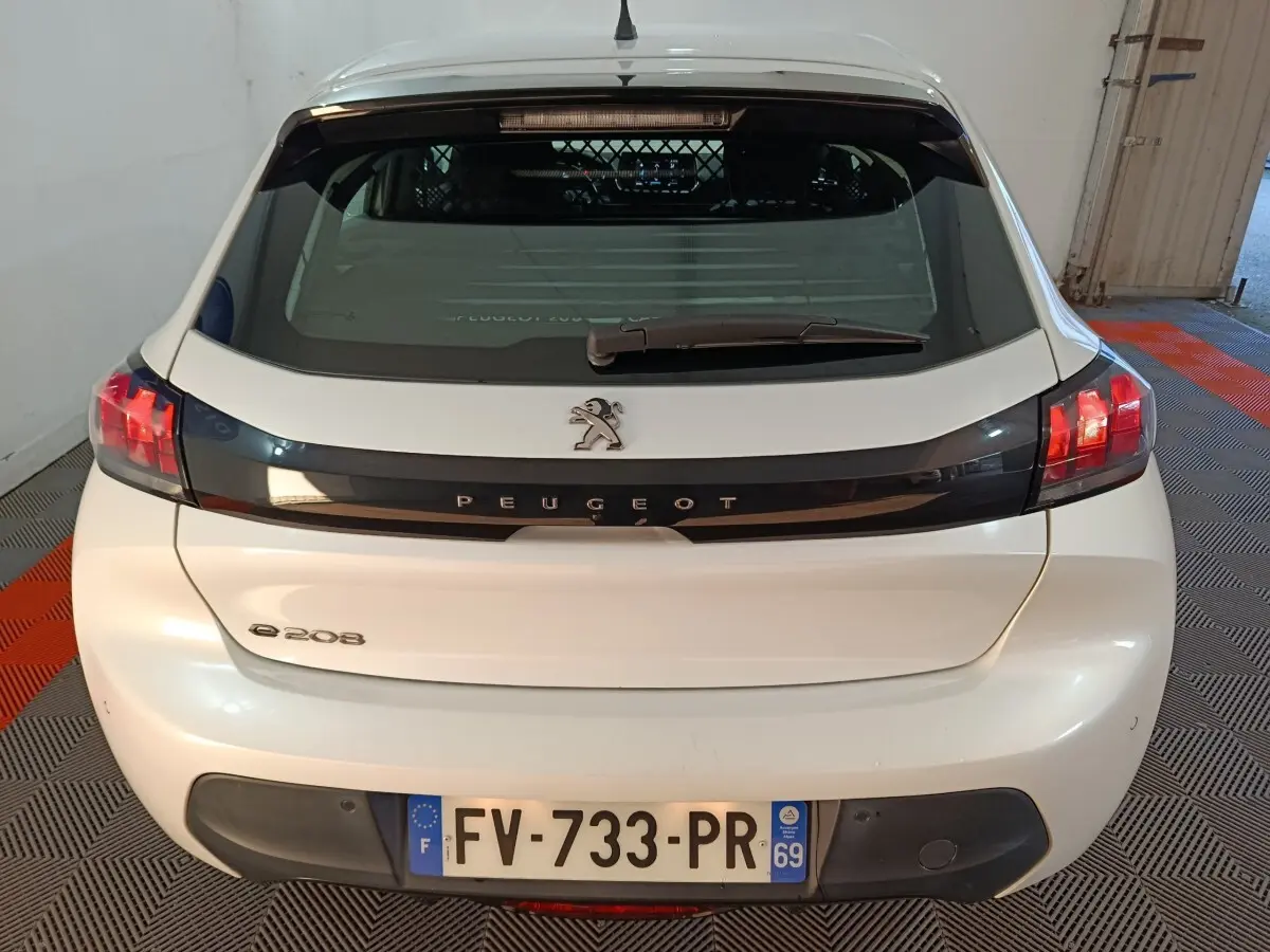 Vue arrière d'une Peugeot 208 électrique blanche avec logo et plaque d'immatriculation française visible.
