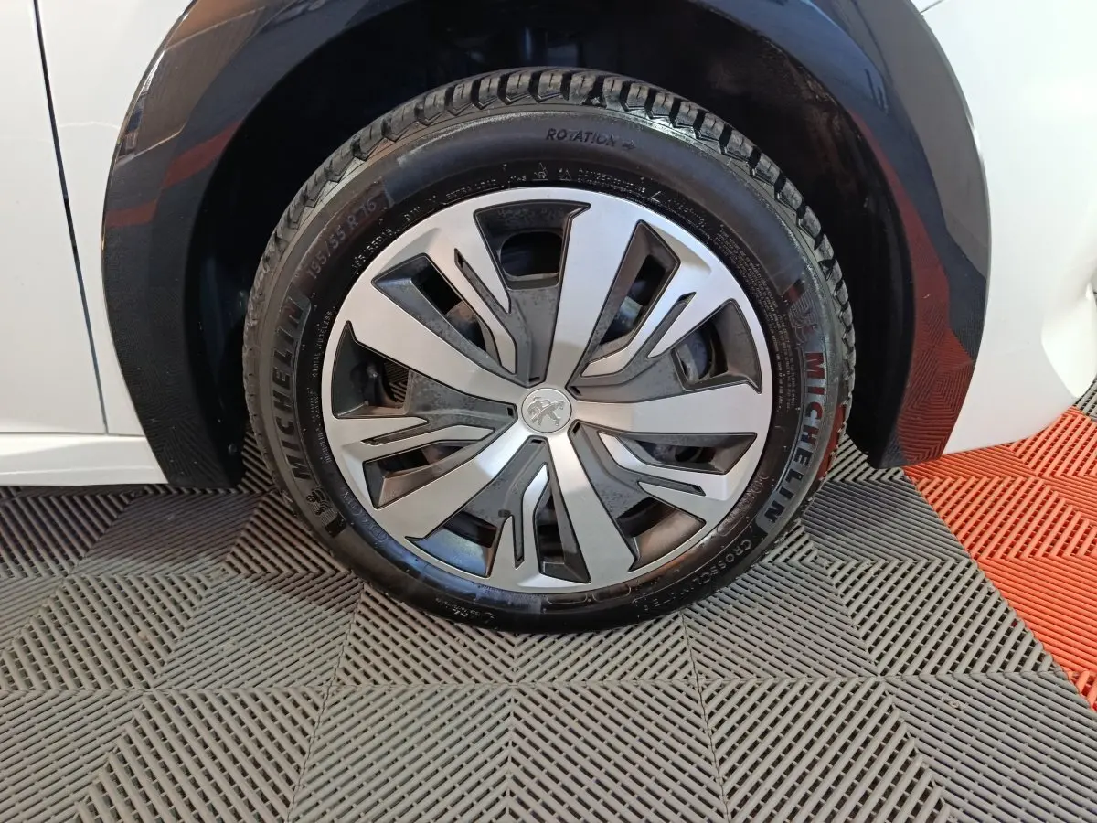 Gros plan sur la roue avant droite de la Peugeot 208 électrique blanche, avec jante alliage et pneu Michelin.