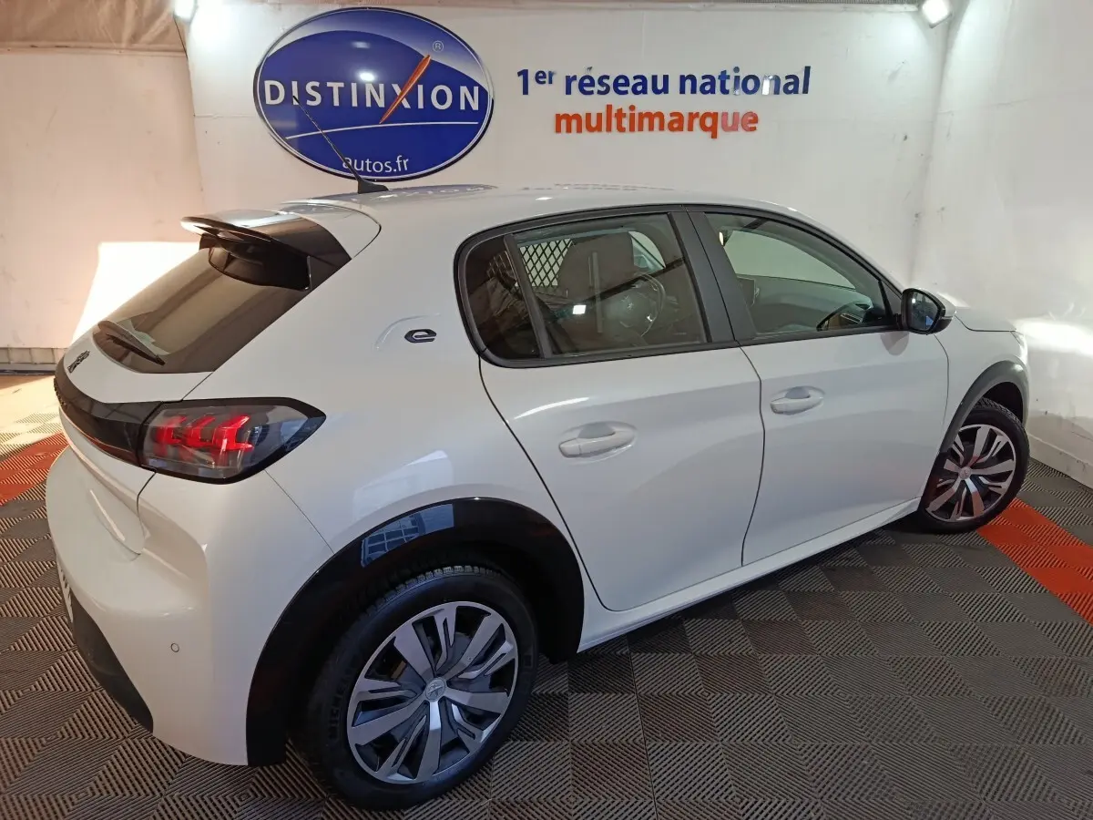 Vue 3/4 arrière droite d'une Peugeot 208 électrique Active Business blanche avec feux LED et jantes spécifiques.