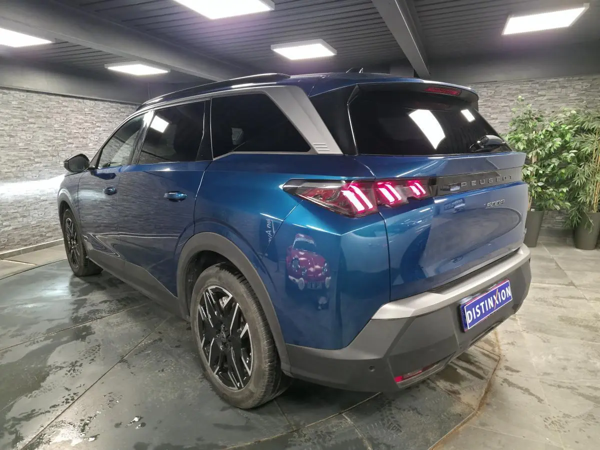 Peugeot 5008 bleu métallisé en 3/4 arrière droit, feux arrière LED à 3 griffes et jantes alliage 19 pouces.