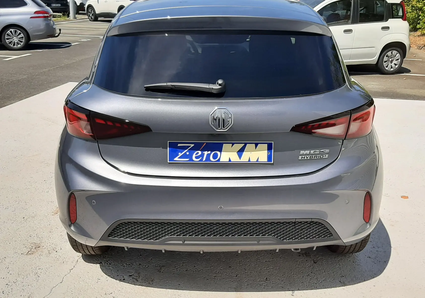 Vue arrière d'une MG3 1.5L Hybrid+ 195ch Luxury gris Hampstead, avec vitres teintées et logo MG visible.