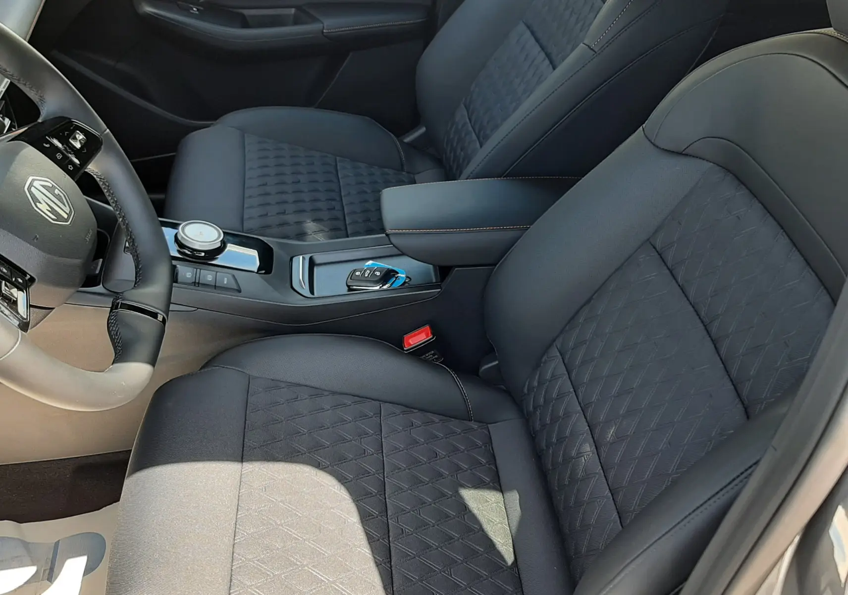 Vue intérieure côté conducteur du MG3 1.5L HYBRID+ 195CH Luxury avec sièges noirs en tissu et cuir, console centrale moderne.