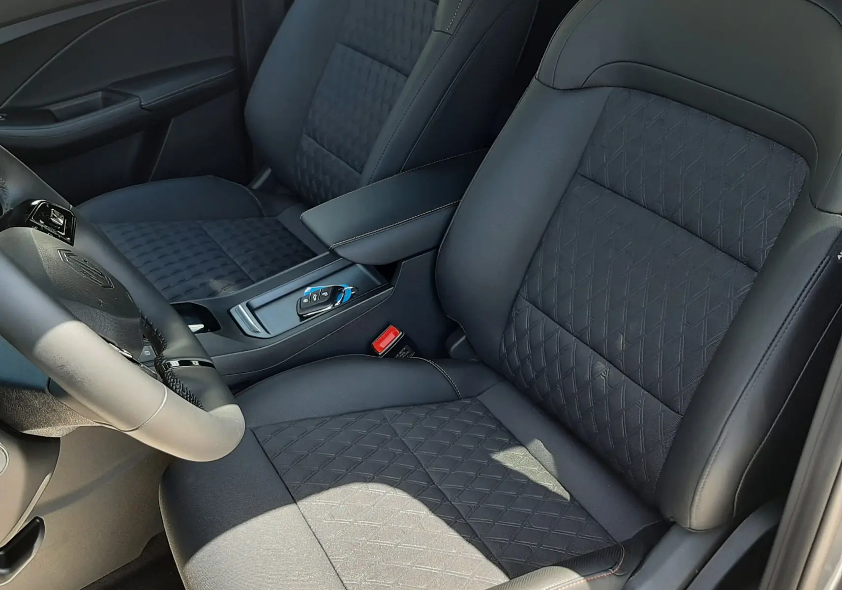 Vue intérieure rapprochée des sièges avant noirs avec surpiqûres orange du MG3 1.5L HYBRID+ 195CH LUXURY 2026.