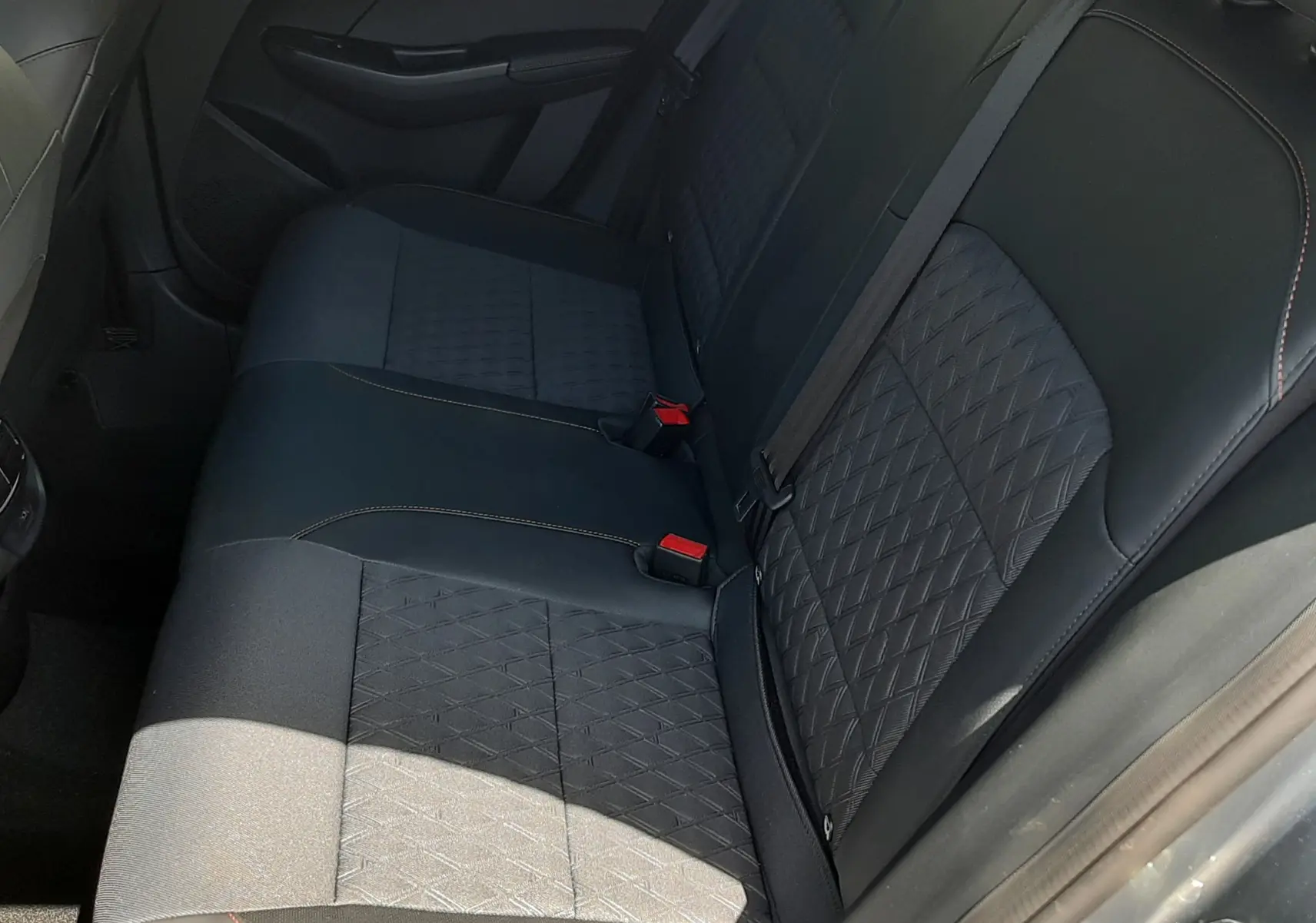 Vue intérieure côté droit des sièges arrière en tissu noir avec surpiqûres orange de la MG3 1.5L Hybrid+ 2026 couleur Hampstead Grey Metal.