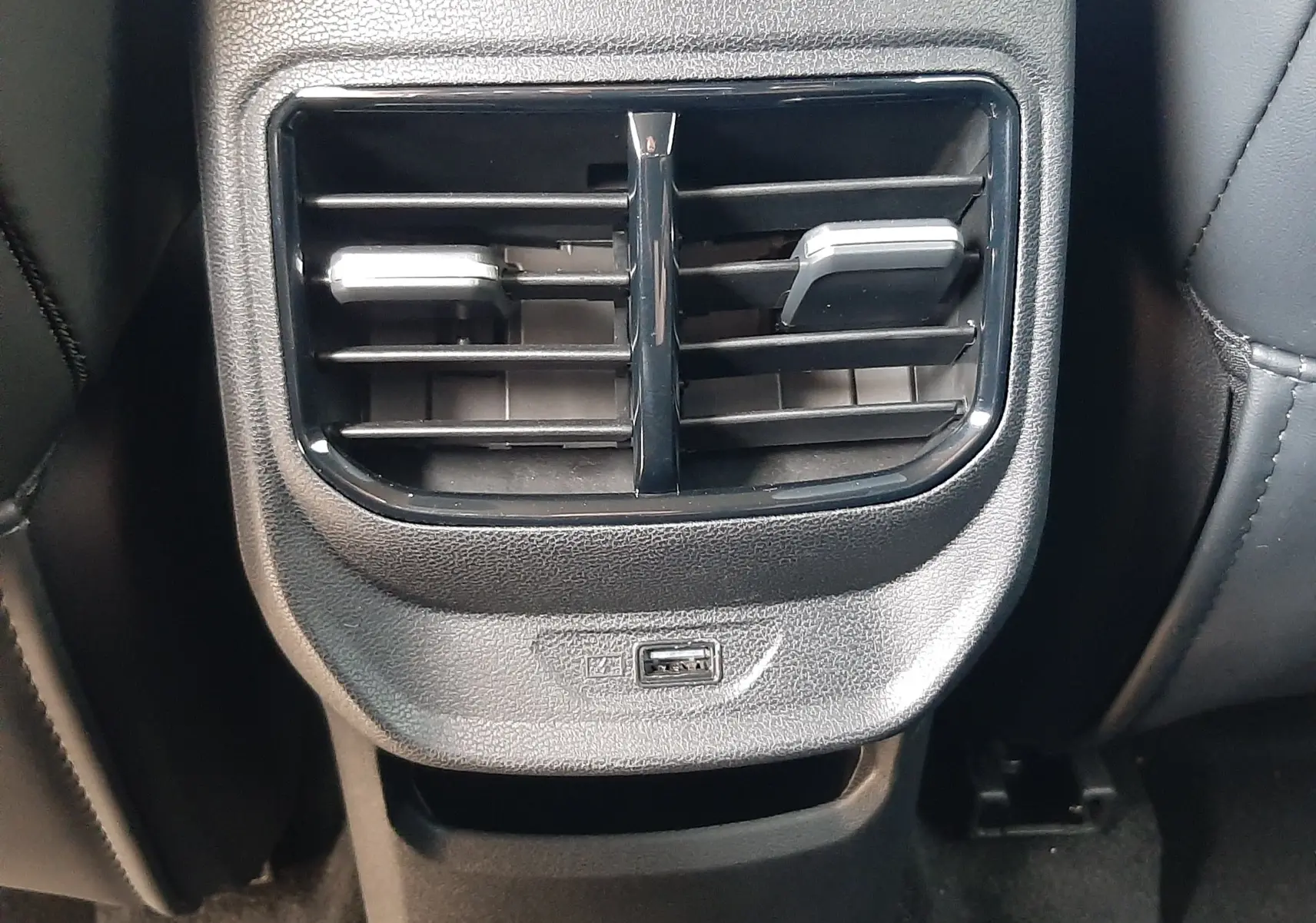 Gros plan sur la sortie d'air arrière noire avec réglages et port USB du MG3 1.5L Hybrid+ 2026 en intérieur sombre.