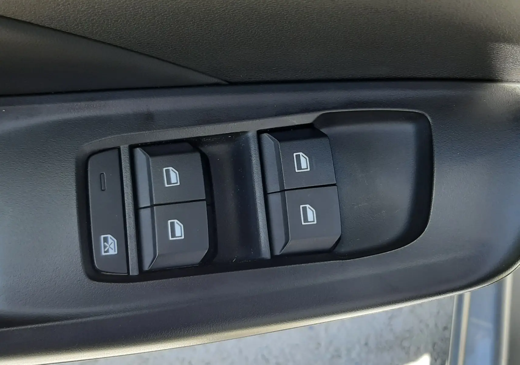 Gros plan sur les commandes de lève-vitres côté gauche d'une MG3 1.5L Hybrid+ gris Hampstead, intérieur noir.