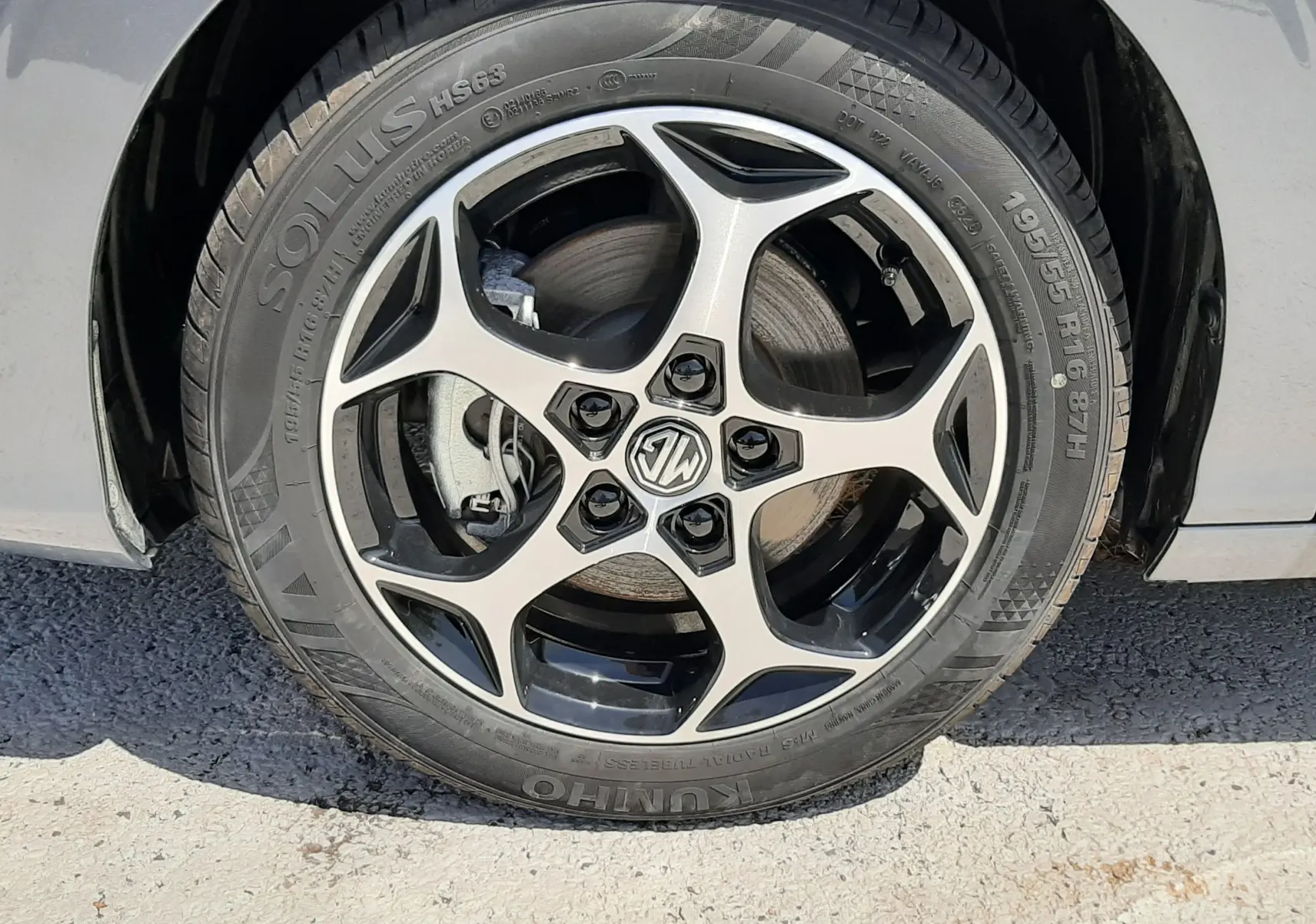 Gros plan sur la roue avant droite d’une MG3 1.5L HYBRID+ 195CH Luxury en gris Hampstead avec jante alliage noire et argent.