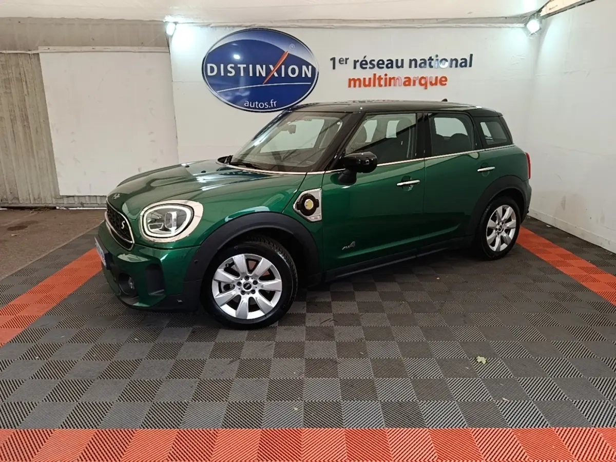 Vue de profil droit d'une MINI Countryman hybride rechargeable vert foncé avec toit noir en intérieur showroom.