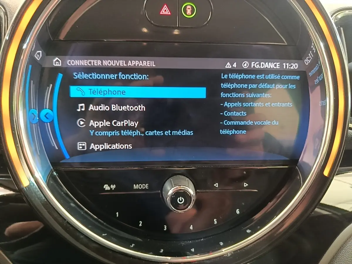 Gros plan sur l'écran tactile circulaire du tableau de bord du MINI Countryman gris clair affichant les options Apple CarPlay et Bluetooth.