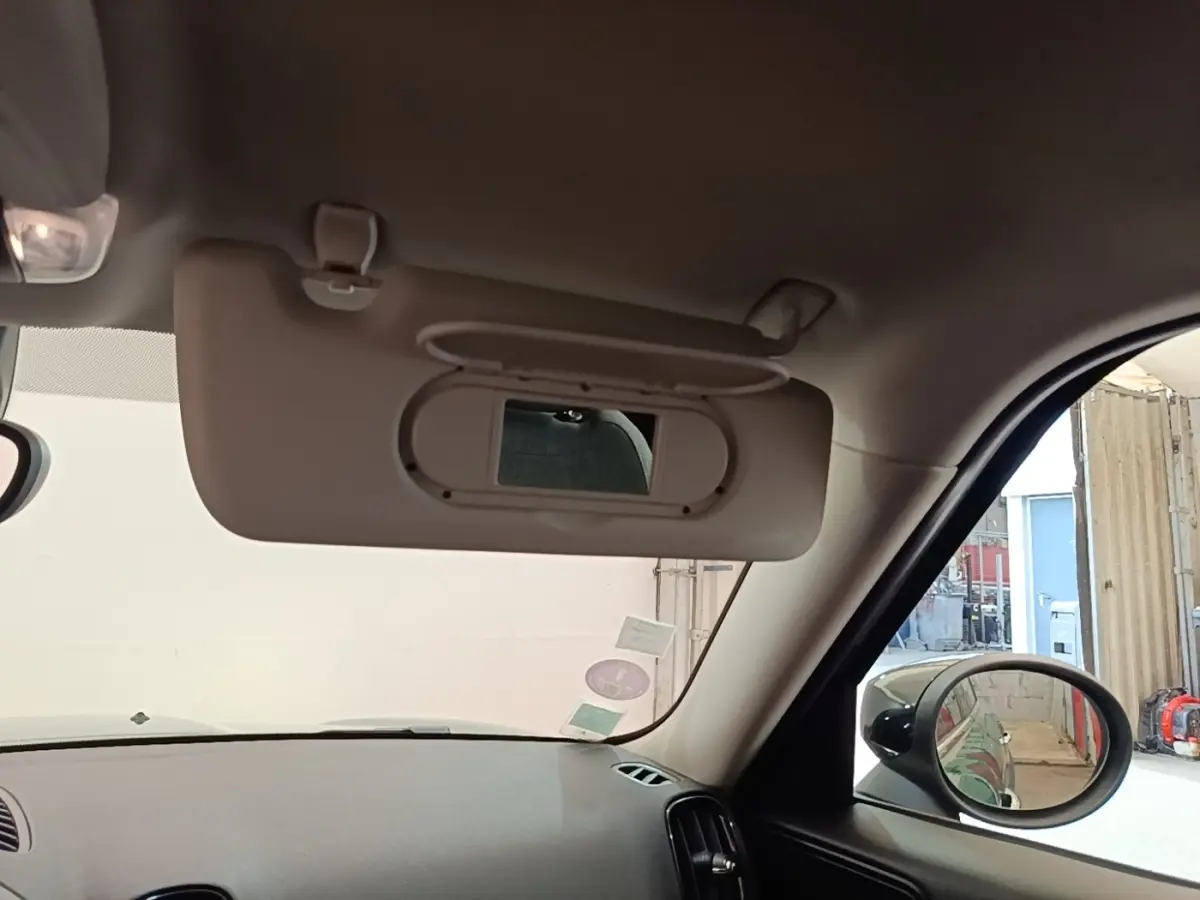 Intérieur du MINI Countryman Cooper SE 2021, vue côté passager avec pare-soleil beige et rétroviseur extérieur noir.