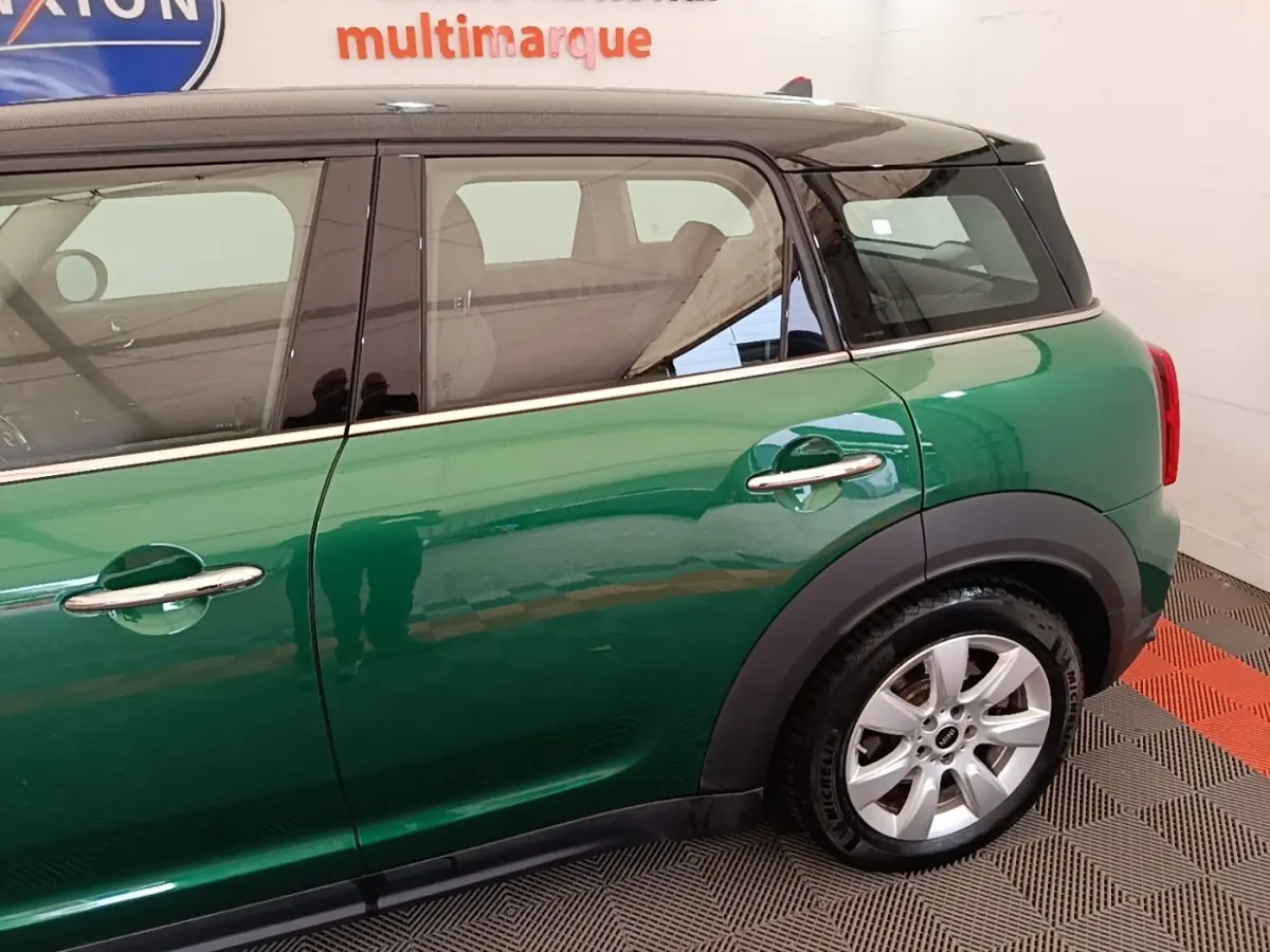 Vue latérale droite d'une MINI Countryman hybride rechargeable vert foncé avec toit blanc et jantes argentées.