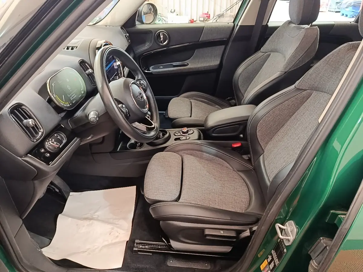 Vue intérieure côté conducteur d'une MINI Countryman hybride rechargeable avec sièges tissu gris et volant cuir noir.