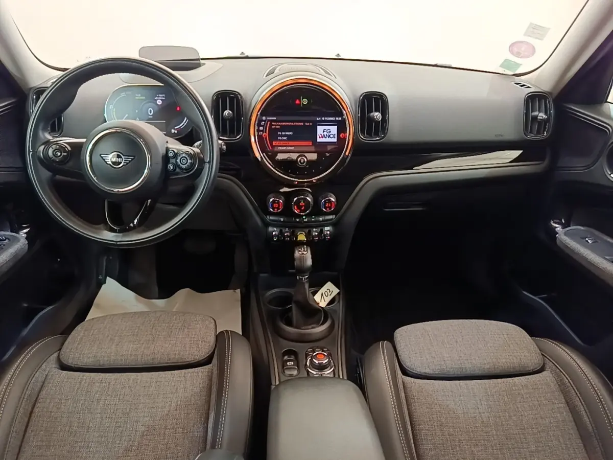 Intérieur avant du MINI Countryman Cooper SE gris clair, tableau de bord moderne avec écran central rond et volant multifonctions.
