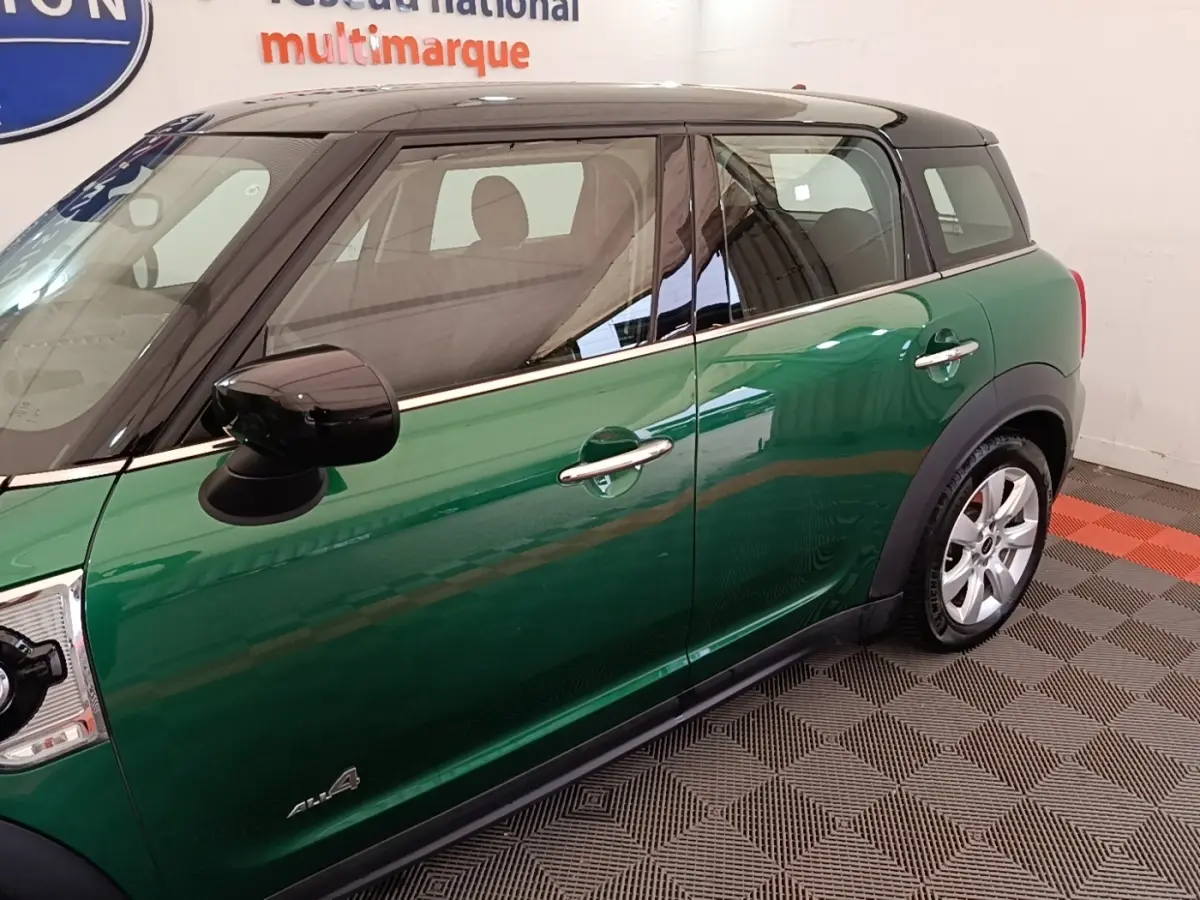 Vue latérale droite d'une MINI Countryman hybride rechargeable verte avec toit noir et jantes argentées.