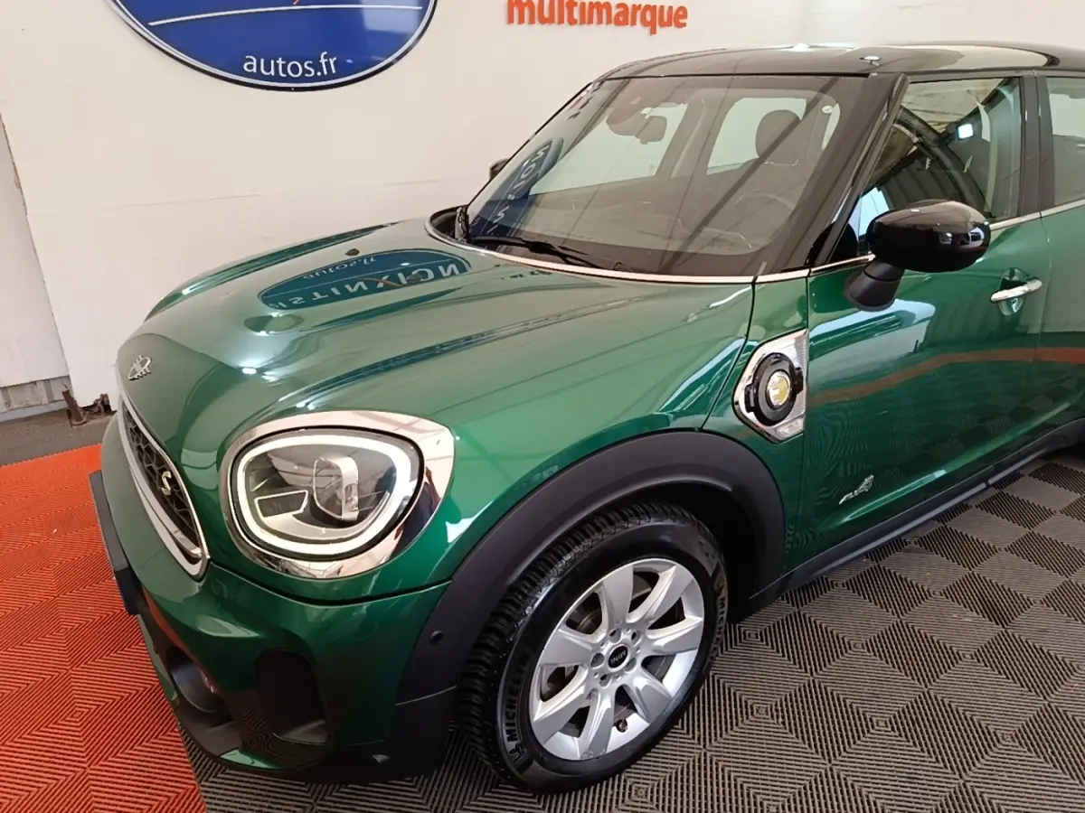 Vue 3/4 avant droit d'une MINI Countryman Cooper SE hybride rechargeable vert foncé avec toit noir et jantes argentées.