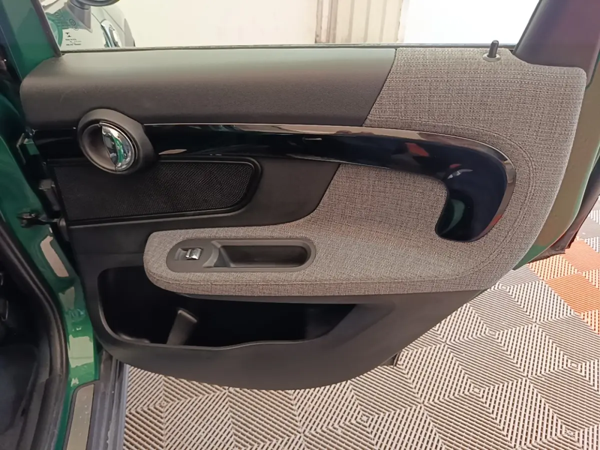 Vue intérieure côté gauche de la porte avant d'une MINI Countryman gris clair avec habillage tissu et plastique noir brillant.