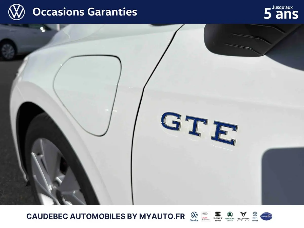 Gros plan côté gauche sur l'emblème GTE et la trappe de recharge d'une Volkswagen Golf 1.5 eHybrid blanche.