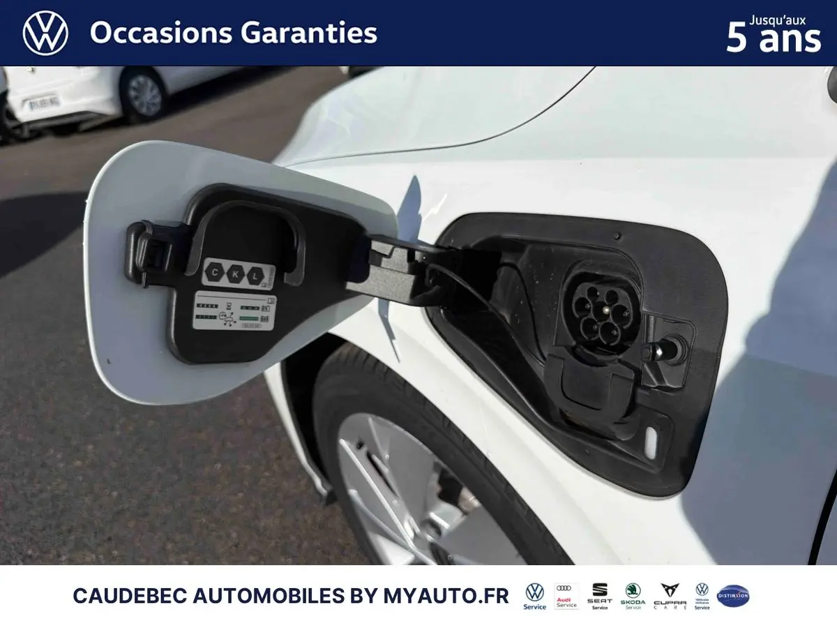 Prise de recharge ouverte côté gauche d’une Volkswagen Golf 1.5 eHybrid blanche, jante visible en arrière-plan.