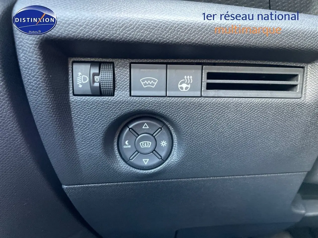 Détail du tableau de bord noir de la Citroën C4 2024 montrant les commandes de réglage des phares et du volant chauffant.