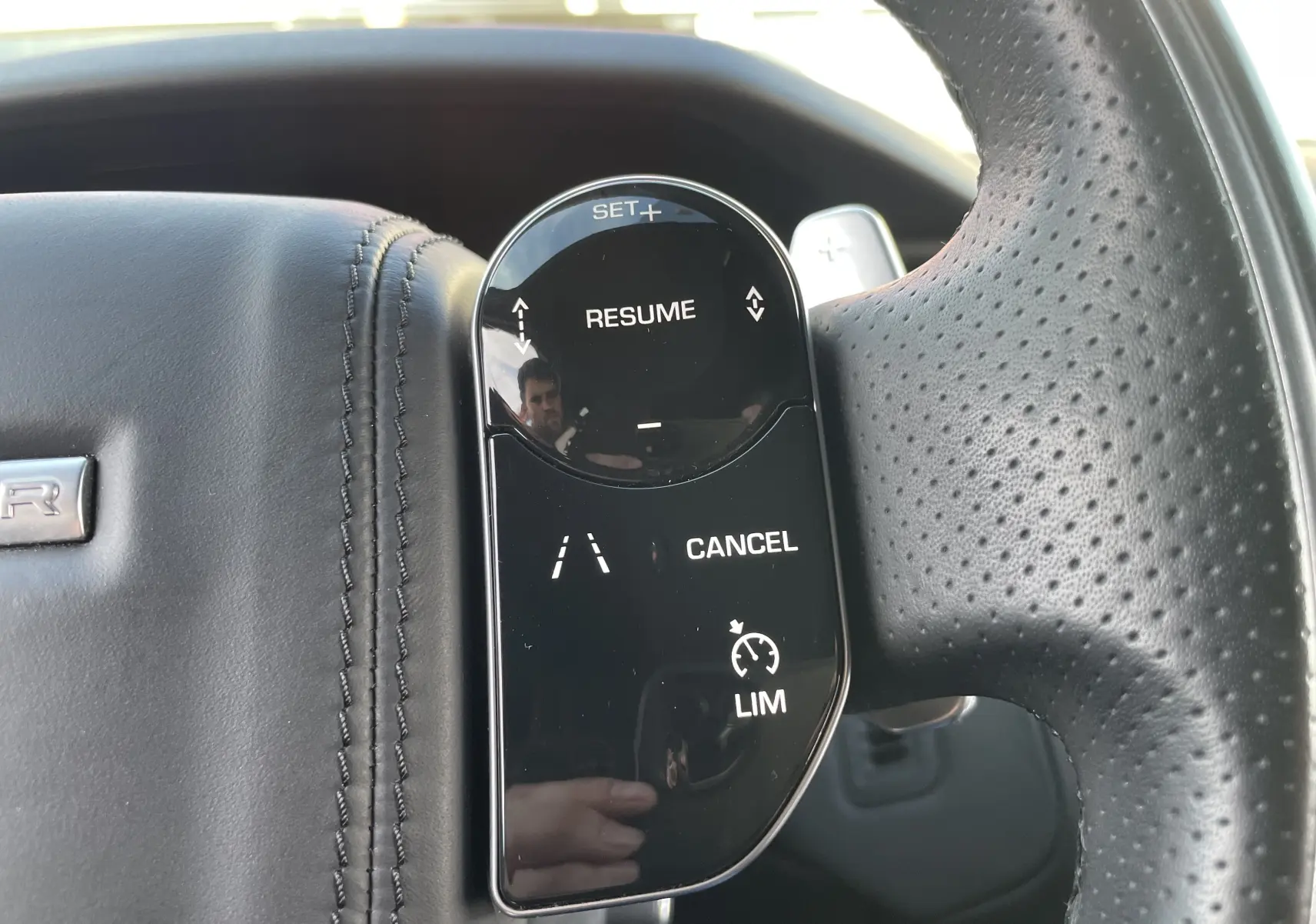 Gros plan sur les commandes du régulateur de vitesse au volant en cuir noir perforé du Range Rover Velar 2019.