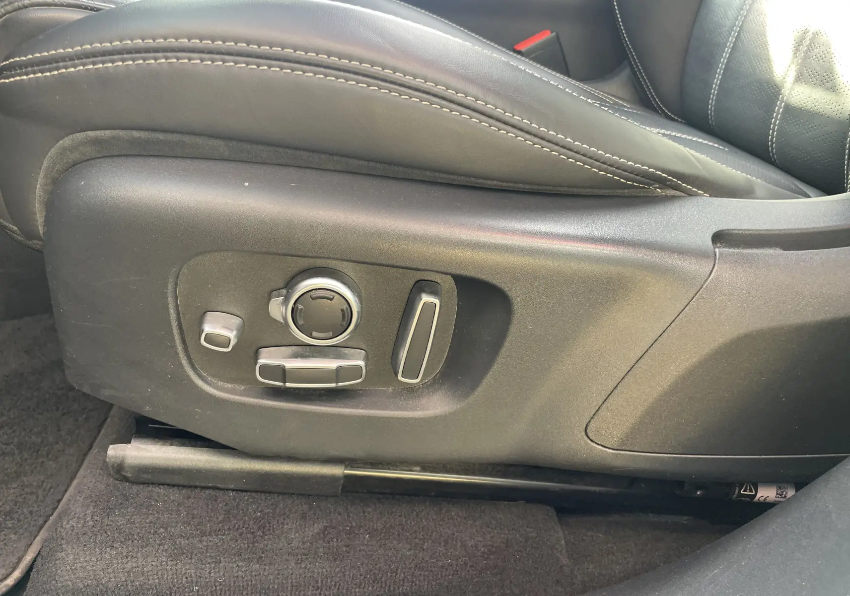 Gros plan sur les commandes électriques du siège en cuir noir avec surpiqûres blanches du Range Rover Velar 2019.