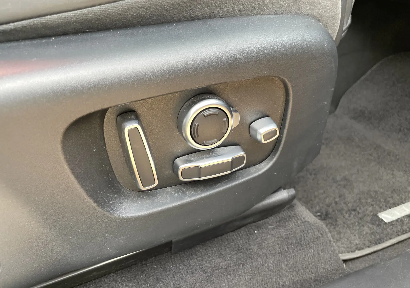 Gros plan sur les commandes électriques de réglage du siège côté conducteur du Range Rover Velar noir Santorini 2019.