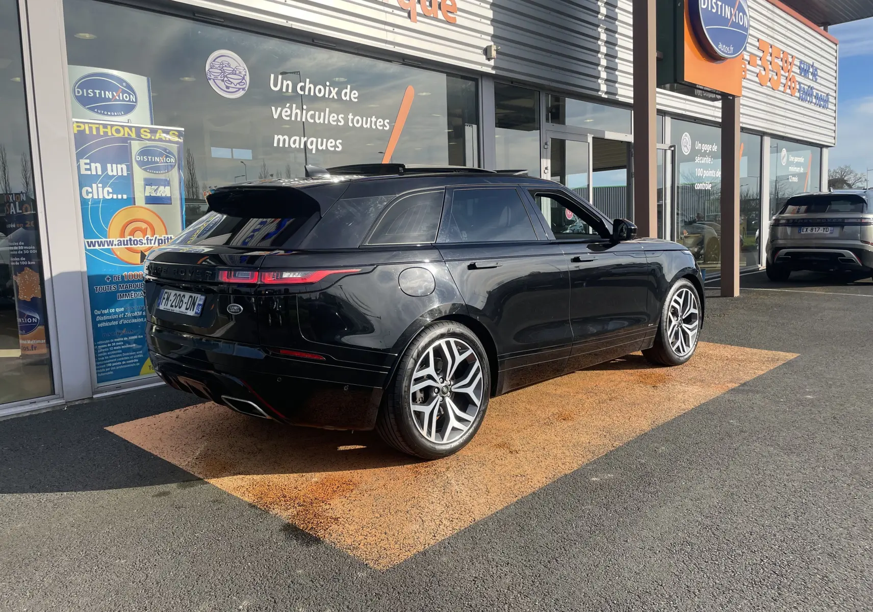 Range Rover Velar noir Santorini vu en 3/4 arrière droit, avec jantes alliage distinctives et vitres teintées.